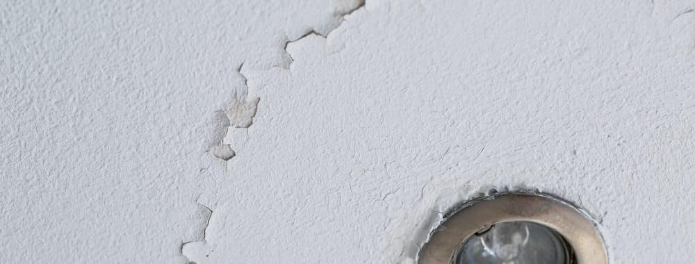 ceiling with cracks and peeling paint around led can light from water damage