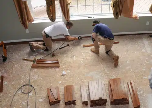 contractors laying down wood flooring in living room after water damage occurred