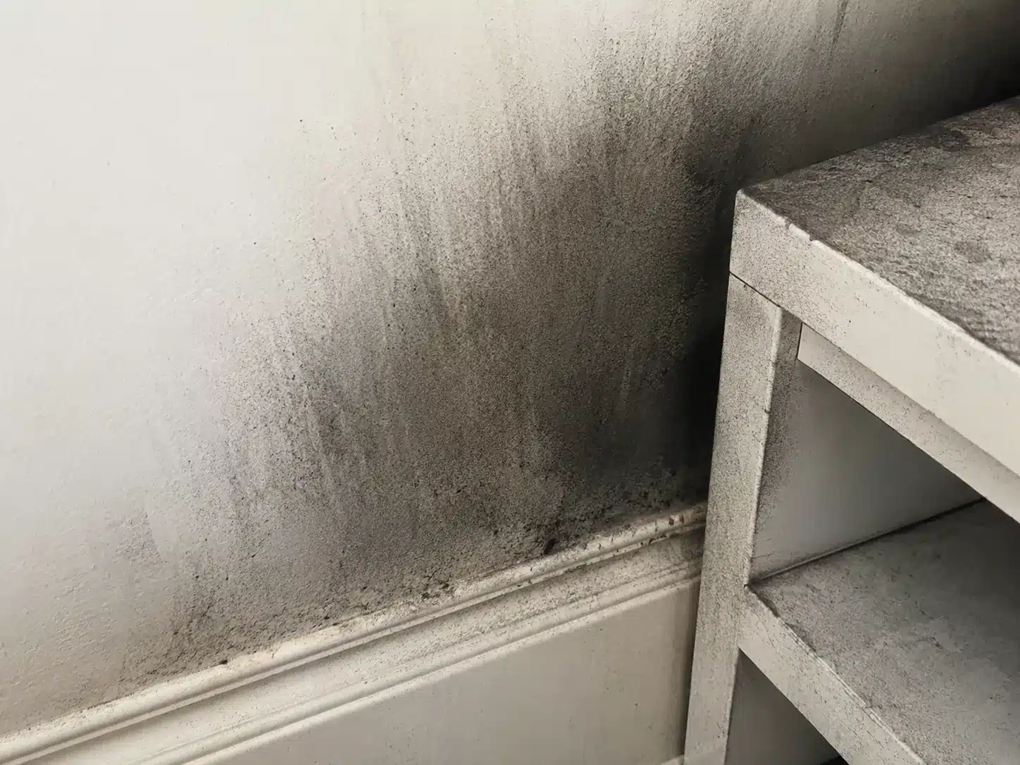 Black soot residue on a wall and cabinet after a property fire